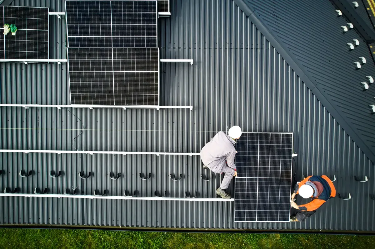 Vista aérea de instaladores colocando paneles sobre una cubierta, como la azotea de un bloque de pisos de Badalona